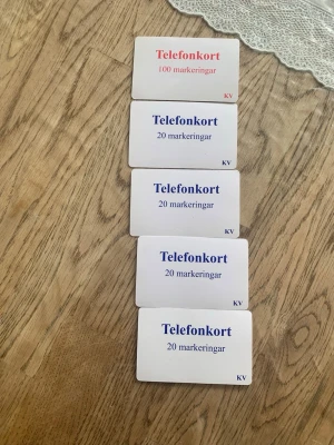 Samling telefonkort med markeringar - Telefonkort för anhöriga till intagna. Fem telefonkort i plast, fyra vita med blå text och 20 markeringar vardera samt ett vitt med röd text och 100 markeringar. Allt för 500 