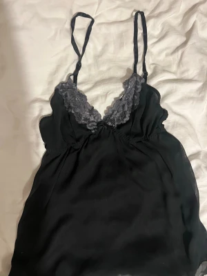 gammalt linne intimissimi - Snyggt svart nattlinne från intimissimi med tunna axelband och dekorativ grå spets runt urringningen. Mjuk och följsam känsla, perfekt för mysiga kvällar hemma. Lätt och luftigt material som ger en avslappnad look. Jättegammalt men BRA kvalitet