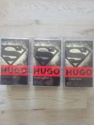 Superman x Hugo parfym 125 ml - Cool parfym från samarbetet Superman x Hugo. Svart och guld förpackning med Superman-logga och röd Hugo-text. Flaskan innehåller 125 ml och är perfekt för dig som gillar snygg design och vill sticka ut med din doft. Det är tre helt oöppnade nya parfymer 
