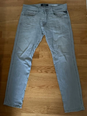 Ljusgrå jeans Replay - Säljer ett par ljusgrå jeans från Replay i modell Anbass strl 33. Se sista bilden för liten röd fläck på baksidan som ej gått bort, värt att testa igen. 