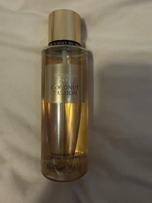 Victoria's Secret Coconut Passion mist - Fräsch body mist från Victoria's Secret i doften Coconut Passion. Flaskan är genomskinlig med guldfärgat lock och etikett. Innehåller 250 ml och har en tropisk, söt kokosdoft. Perfekt för dig som älskar fruktiga och exotiska parfymer.