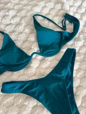 Mörkgrön bikini med triangeltopp - Snygg mörkgrön bikini med enkel triangeltopp och matchande bikinitrosa. 