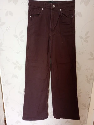 Bruna raka jeans med hög midja - Säljer ett par bruna jeans med rak passform och hög midja. Klassisk femficksmodell med knapp och dragkedja framtill. Jeansen har en enkel och stilren look, perfekta till vardagsoutfits. Materialet känns som bomull med lite stretch.