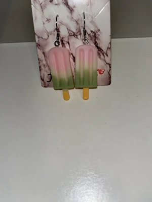 Glasspinne örhängen i pastell - Säljer ett par unika örhängen formade som glasspinnar i pastellfärger. Örhängens krokarna är i rostfritt stål 