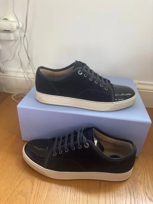 Mörkblå sneakers från Lanvin - Hej 👋 jag säljer dessa feta lanvins! Storleken är är uk 10 eller 44/45 Dom är nästan helt nya och har endast använts ett fåtal gånger. Köpta på Care of Karl. Fråga om orderbekräftelse🙌skick 9/10 finns bara en liten defekt, fråga om bild.