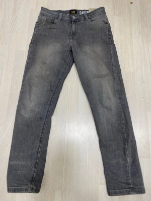 Grå jeans Lee Daren - Säljer ett par grå jeans från Lee, modell Daren. Klassisk femficksdesign med raka ben och knappgylf. Jeansen har en snygg tvättad look och är tillverkade i slitstarkt denimtyg. Perfekta för en avslappnad och trendig stil. Slim jeans