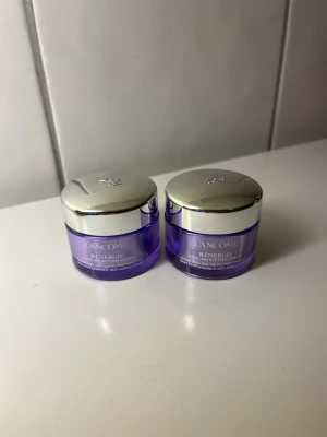 Lancôme Rénergie ansiktskräm duo 15x2 ml NYA - Två burkar Lancôme Rénergie ansiktskräm i lila plast med silverfärgade lock. Varje burk rymmer 15 ml och har en elegant, rund form. Perfekt för dig som vill boosta hudvårdsrutinen med en lyxig anti-age kräm.