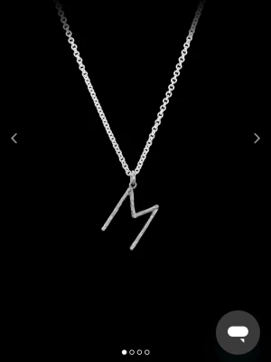 Maria Nilsdotter halsband med L bokstav - Snyggt halsband i silverfärgad metall med ett hänge i form av bokstaven L. Kedjan är tunn och stilren. Från Maria Nilsdotter i bra skick och köptes för 2000 i butik. 