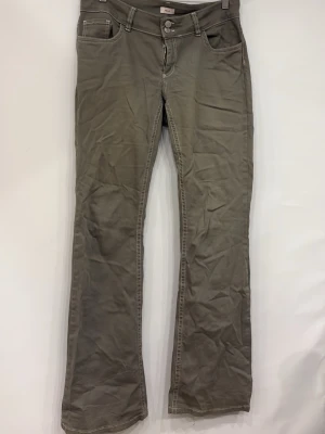 Grå bootcut jeans med kontrastsömmar - Snygga grå jeans med bootcut-modell och vita kontrastsömmar. Klassisk femficksdesign och dubbla knappar i midjan. Jeansen har en avslappnad passform och är tillverkade i ett mjukt bomullstyg. Perfekta för en trendig och avslappnad stil.