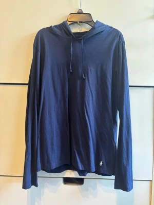 Marinblå hoodie från Polo Ralph Lauren - Snygg marinblå hoodie från Polo Ralph Lauren. Den är tunn och i storlek S. Nypris 799kr. Bara använd någon enstaka gång. Hör av er vid intresse eller frågor!