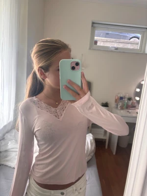 Ljusrosa långärmad top - Supersöt ljusrosa långärmad topp från Gina Tricot med spetsdetalj och v-ringning. Perfekt att styla med jeans eller kjol för en chill look. Mjuk och skön, passar dig som gillar feminina detaljer.