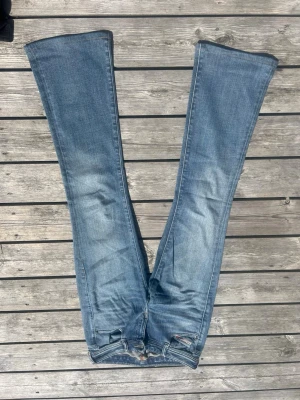 Blå bootcut jeans från Diesel, stl W26, passar 172cm lång - Säljer ett par blå bootcut jeans från Diesel med klassisk femficksmodell och snygga slitningar. Jeansen har en ljus tvätt och markerade sömmar. Perfekta för dig som gillar retrovibbar och vill ha ett par jeans med riktigt schysst passform.