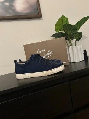 Christian Louboutin skor  - Säljer ett par mörkblå Christian Louboutin-skor i storlek 41. Skorna är använda cirka fem gånger och är överlag i mycket fint skick.   Två av de dekorativa spikarna saknas (se bilder), men detta påverkar inte funktionen och syns inte särskilt mycket vid användning.  Storlek: 41 Färg: Mörkblå Använda: Ca 5 gånger Skick:  fint skick  (två saknade spikar) men det kommer med 3 spikar i en liten förpackning  Hör gärna av dig om du vill ha fler bilder eller har några frågor.