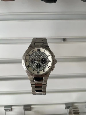 Stilren silverfärgad kronografklocka - Säljer en snygg och robust kronografklocka i silver med metallarmband. Urtavlan har flera mindre visare och tydliga siffror runt om. Klockan har en sportig men ändå klassisk look och passar perfekt till dig som gillar detaljer. Märke champion 