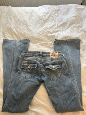 Joey Ljusblå True Religion Jeans - Säljer ett par ljusblå True religion jeans i storlek W24. Fick dessa för 2 månader sen men har använts ca 3 gånger. De ända negativa me dessa är att jag trampade sönder nedre delen av ena sidan av byxorna första gången jag använde de men annars är jeansen i jättebra skick. 