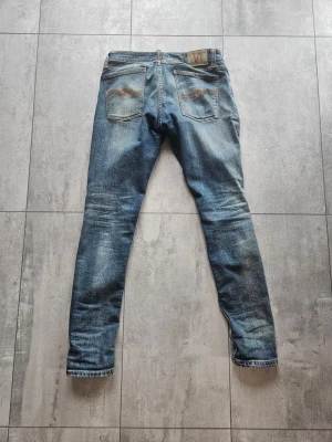 Nudie Jeans Skinny Lin blå jeans 32/32 - Säljer ett par riktigt snygga Nudie Jeans i modellen Skinny Lin och storlek 32/32. Jeansen har en klassisk blå tvätt med snyggt slitna detaljer och en smal passform. De är i mycket gott skick, väl omhändertagna och helt utan skador. Kom med prisförslag och det är bara att skriva om ni har frågor!