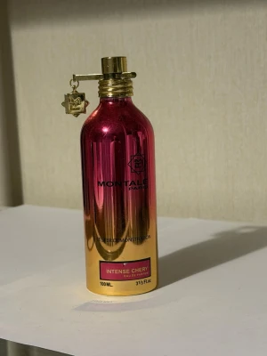 Montale Intense Cherry parfym 100ml - Montale Intense Cherry är en parfym i en metallisk flaska med rosa och guld färgskiftning. Flaskan har en unik guldfärgad kork med en dekorativ berlock. Doften är känd för sina intensiva körsbärsnoter och flaskan rymmer 100 ml.