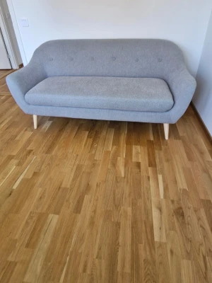 Jysk Ljusgrå soffa med träben - Säljer en stilren ljusgrå soffa med mjukt tyg och rundade former. Soffan har knappar i ryggen och ljusa träben som ger en modern känsla. Perfekt för vardagsrum eller studentrum.
