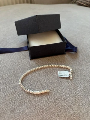Plomberad Silverarmring 925 – Oanvänd – Sterlingsilver - Säljer en stilren silverarmring i äkta 925 sterlingsilver. En student present som tyvärr inte kommer till användning. Armbandet är fortfarande plomberat och oanvänt, vilket gör det perfekt som present eller för dig som vill ha ett helt nytt smycke. Levereras i originalask.  Armbandet är i nyskick och stämplat med 925 för sterlingsilver. En tidlös och elegant modell som passar både till vardag och fest.
