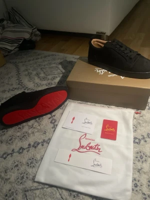 christian louboutin - Stilrena svarta christian louboutin i mockaliknande material med svarta skosnören och en unik röd undersida med grafiskt mönster. Låg modell med diskret design och beige insida. Perfekta för dig som gillar minimalistisk stil med en twist.