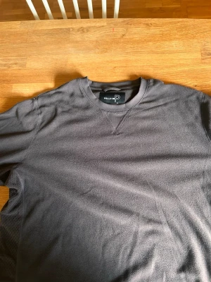 Mörkgrå sweatshirt från Pelle P - Mörkgrå sweatshirt från Pelle P med rund halsringning och långa ärmar. Tröjan har diskreta sömdetaljer och meshpaneler längs ärmarna för extra ventilation. Perfekt för en avslappnad och sportig stil. Andvänd nästan en gång.