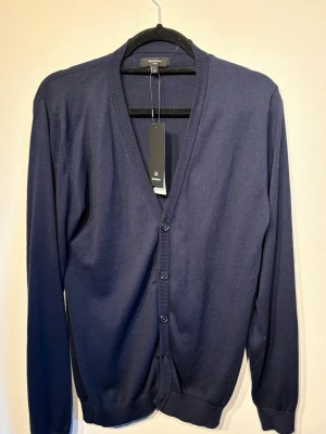 Mörkblå cardigan från Matinique - Stilren mörkblå cardigan från Matinique med v-ringning och knäppning framtill. Tillverkad i mjukt, tunt material som passar perfekt för lager på lager. Klassisk ribbad kant vid ärmslut och nederkant. Enkel att matcha med olika outfits. Priset kan diskuteras 