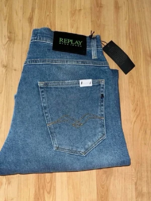 Nya Replay Anbass jeans  - Helt nya! Repaly Kyran Jeans som har en rak passform med flera slitningar och hål på vänster knä. Midja 37cm, längd 109cm. Obs liten defekt vid sidan av benet. JAG SKICKAR EJ FLER BILDER NÄR JAG BÄR JEANSEN! för bättre inblick i passformen rekommenderar jag att googla på modellnamnet. För storleksguide kolla måtten noggrant då jeansen alltid kan vara uppsydda heller krympta och jag ej tar emot returer :) Nya6