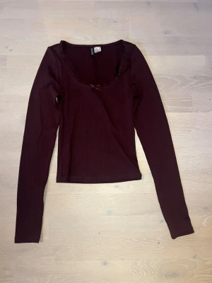 Vinröd ribbad långärmad topp H&M - Perfekt till hösten🍁🤎Mörkröd långärmad topp med ribbad struktur och rundad urringning. Dekorativ liten rosett framtill och diskret volangkant vid halsen. 