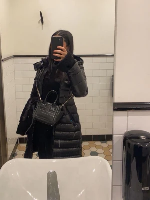 Lång moncler dunjacka - Lång äkta moncler dunjacka med svart glansig finish & quiltad modell med markerad siluett. Använd en vinter. I strl S. Går att hämta upp på plats.