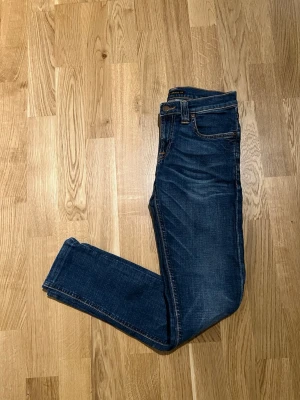 Nudie Jeans - Storlek 25/32 - Stilfulla Nudie Jeans för män. Passform: Thight / Slim. Storlek Waist 25 / Lenght 32. Nyskick, inga defekter/slitage. Hör av dig vid intresse/frågor. PRIS KAN DISKUTERAS!