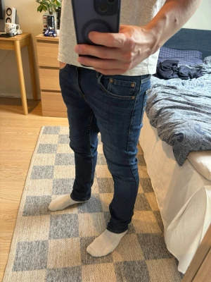 Mörklblå Levis 512 s jeans  - Säljer ett par Levi’s 512 Slim jeans i mörkblå denim, modell “Slim Taper”. Storlek 16A, motsvarar ungefär Small/W28-29.  Sitter lite extra slim just på mig då dem är för små för mig… Bra skick utan hål eller fläckar, fint slitage i tvätten. Klassisk 5-fickors modell med kontrastsömmar i orange/gult och äkta Levi’s läderlapp på baksidan.  Perfekta för vardagsbruk – smal passform utan att vara alltför åtsittande. 