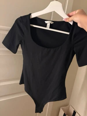 Svart basic body med kort ärm - En enkel och stilren svart body med korta ärmar och rundad urringning. 