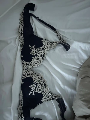 mörkblå intimmismi bh push up! - Snygg mörkblå bh med vacker vit spetsbrodyr över kuporna och längs kanterna. Justerbara axelband och bygel för extra stöd. Elegant design med blommönster i spetsen som ger en lyxig känsla. jättesöt men passar inte längre! pris kan diskuteras!!🥰