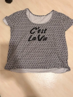 Mönstrad t-shirt från esmara - Säljer en svartvit t-shirt från esmara med coolt grafiskt mönster och texten 'C'est La Vie' framtill. Kan användas som pyjamas eller ute T-shirt. Strl L men passar även M!