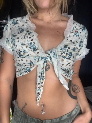 Sorbet vintage floral sequin top - Superfin och unik topp från Sorbet med romantiskt blommigt mönster i vitt/creme och blått, dekorerad med massor av små skimrande paljetter ✨🌸  Toppen har en gullig wrap-/knytmodell framtill, volangdetaljer runt ärmar och hals samt en feminin, lite boho/Y2K-känsla. Så fin till jeans, kjol eller shorts! Storlek L- men sitter såhär på mig med storlek 38🩵                                                        🤎 BUDAS UT PÅ LIVE! 🤎 Denna kommer att budas ut på min Plick Live 25 augusti kl. 19:00 🛍️