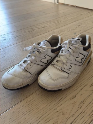 New Balance 550 vita sneakers - Säljer ett par New Balance 550 sneakers i vitt läder med bruna och beige detaljer. Klassisk låg modell med perforerade partier och tydlig logga på sidan. 