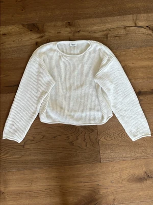 Vit stickad tröja - En enkel och stilren vit stickad tröja med rund halsringning och långa ärmar. Tröjan har en rak passform och är perfekt för lager på lager. Materialet ser mjukt och bekvämt ut, vilket gör den lätt att matcha till olika outfits.