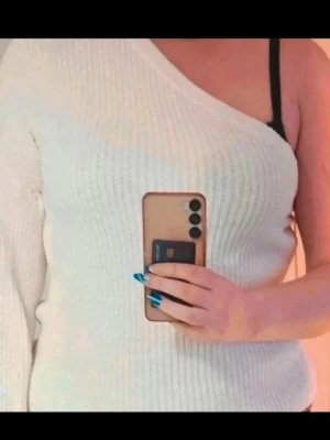 Stickad oneshoulder från Gina Tricot M - Säljer en vit stickad tröja från Gina Tricot i oneshoulder-modell. Tröjan har ribbad struktur och en lång ärm medan andra axeln är bar. Perfekt för dig som vill ha en unik och trendig look. Supermjuk och skön att bära.  Kan även hämtas I Partille  E1
