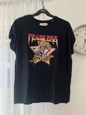 Svart rock tee, storlek xs (s/m) - Svart t-shirt med rock-tryck ”Fearless Tour Rock & Roll”. Storlek XS men oversized, så passar även S/M.  Sälj pga att den inte används längre.