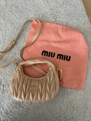Ljusrosa väska från Miu Miu - Supersnygg ljusrosa väska från Miu Miu. Väskan ser beige ut på bilden men är ljusrosa i verkligheten. Väskan har både handtag och justerbar axelrem, perfekt för att bära på olika sätt. Kommer med original dustbag. Nästan aldrig använd.