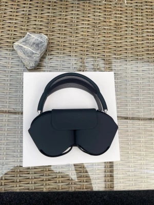 AirPods Max - Stilrena over-ear hörlurar i mörkgrå färg med mjuka öronkuddar och meshband över huvudet. Hörlurarna har en modern design och levereras med ett matchande skyddsfodral. Perfekta för musik, gaming eller poddar.