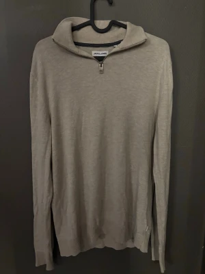Stickad tröja - Tja!! Jag säljer en snygg beige stickad tröja från Jack & Jones med halvzip och hög krage. Tröjan har långa ärmar och ribbade muddar vid ärmslut och nedrekant. Perfekt för lager på lager och enkel att matcha med olika outfits. Vid funderingar är det bara att skriva:))