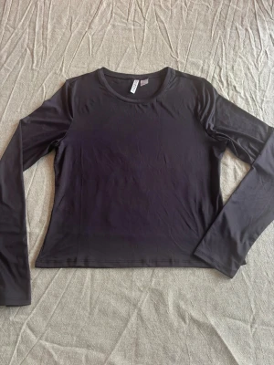 Svart långärmad topp - En enkel och stilren svart långärmad topp med rund hals. Tillverkad i ett mjukt och stretchigt material som sitter skönt mot kroppen. 