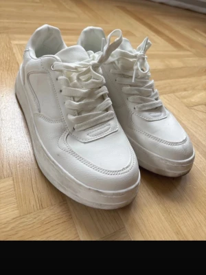 Vita sneakers från ZARA - Stilrena helvita sneakers från ZARA i storlek 37. Skorna har en chunky sula, klassisk låg modell och är tillverkade i syntetmaterial med snörning framtill. Perfekta för dig som gillar en clean och modern look till vardagsoutfiten. Använda endast en gång! Nypris 40 euro köpta i Frankrike 🇫🇷 