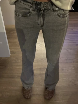 Grå bootcut jeans med låg midja - Säljer ett par grå bootcut jeans med låg midja och klassiska fem fickor. Jeansen har en tvättad look. 