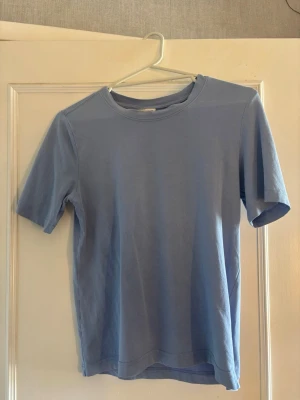 Ljusblå basic t-shirt i bomull - En enkel och stilren ljusblå t-shirt med rund hals och korta ärmar. Tillverkad i mjuk bomull som känns skön mot huden. Perfekt till jeans eller shorts för en avslappnad look.