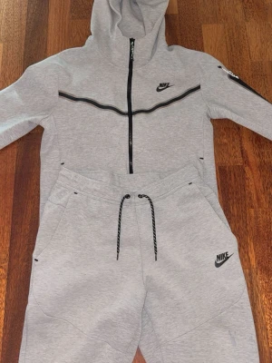 Grå Nike set  - Den klassiska Nike tech settet, väldigt snygg. Den äldsta modellen, men även den snyggaste. Den har en sönder dragkedja där bak på byxan men inget som inte går att använda, lite slitningar de är därför de går för detta pris. Men den är fortfarande användbar och väldigt stilig och snygg att ha på sig samt bekväm.