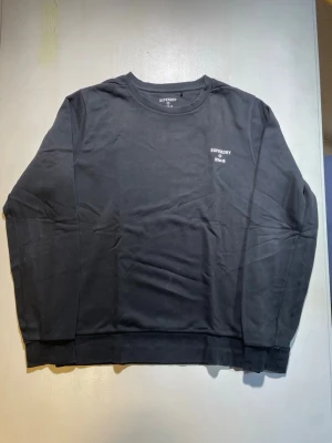 Svart sweatshirt från Superdry - En svart sweatshirt från Superdry med rund halsringning och diskret logga på bröstet. Tröjan har långa ärmar och ribbade muddar vid ärmslut och nederkant. Tillverkad i mjukt bomullsmaterial för en avslappnad look.