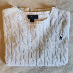 Vit tröja polo Ralph lauren - Jättefin kabelstickad vit tröja från Polo Ralph Lauren! Den har en superfin vit färg och är bara använd ett fåtal gånger. Storlek M 10-12 ungefär som en xs eller lite mindre, perfekt för en tajt fit! Väldigt mysig och passar bra nu till hösten:) Skriv om frågor eller funderingar!