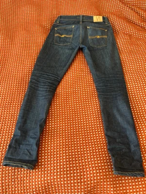  jeans från Nudie Jeans - Snygga mörkblå jeans från Nudie Jeans med klassisk femficksmodell och kontrastsömmar. Jeansen har raka ben och är tillverkade i ett slitstarkt denimtyg. Perfekta för dig som gillar en tidlös och clean look.    Modellen heter Lean Dean och är i materialet dry 16 dips vilket är i raw denim och är riktigt schyssta. Nypris är ca 1800 och säljer dessa för 549 kr